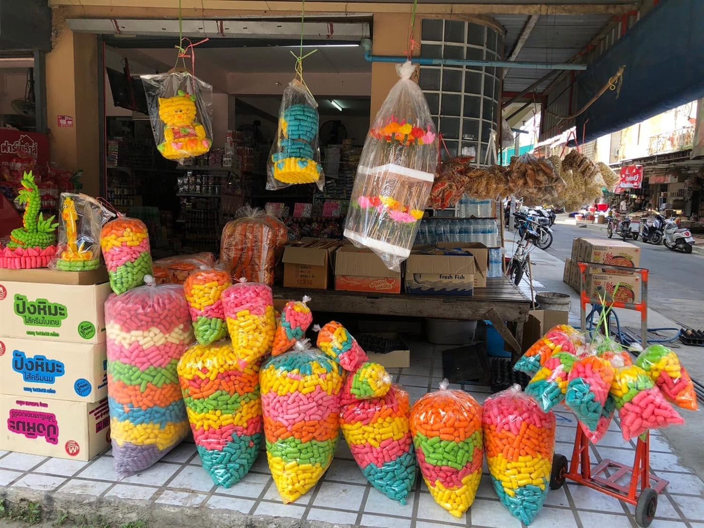 อาหารปลาหลากสีถุงใหญ่และกระทงอาหารปลาวางหน้าร้าน